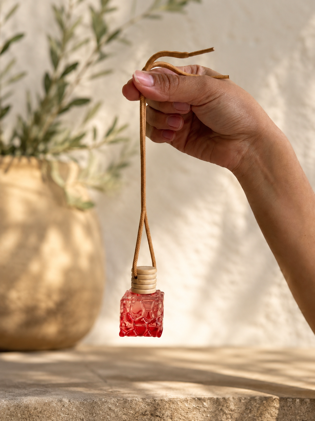 Hand holding a red textured diffuser with a blurred natural background