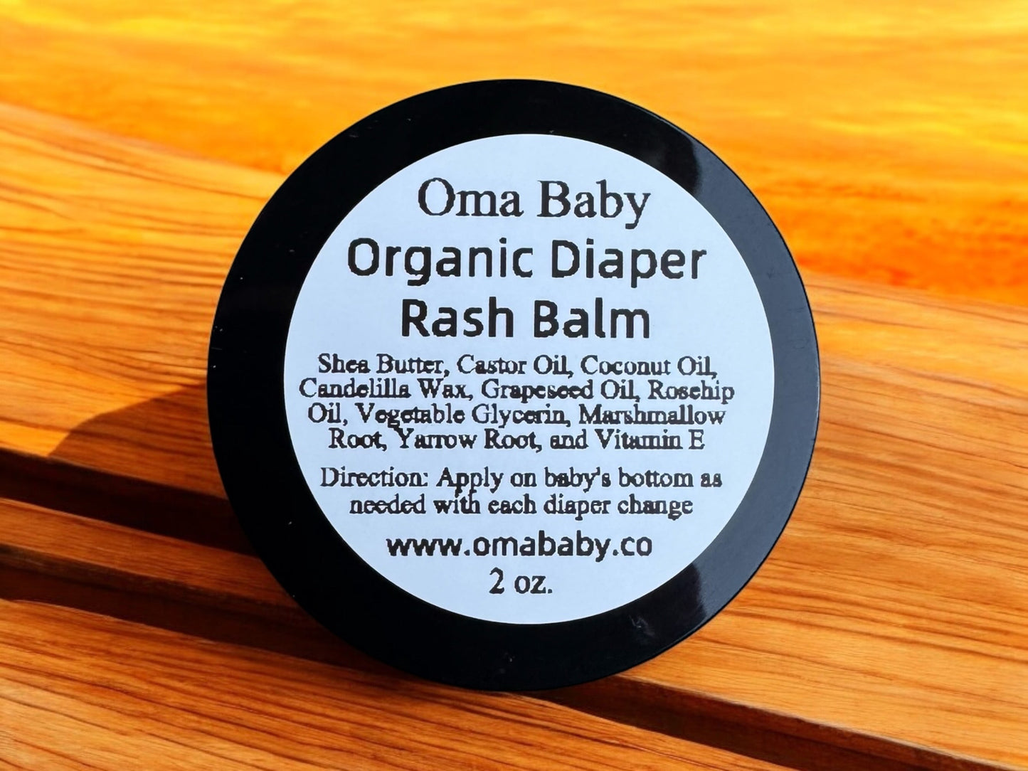 Oma Baby Organic Diaper Rash Balm container on a wooden surface