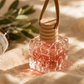 Small glass bottle with wooden cap on a textured surface with greenery in the background