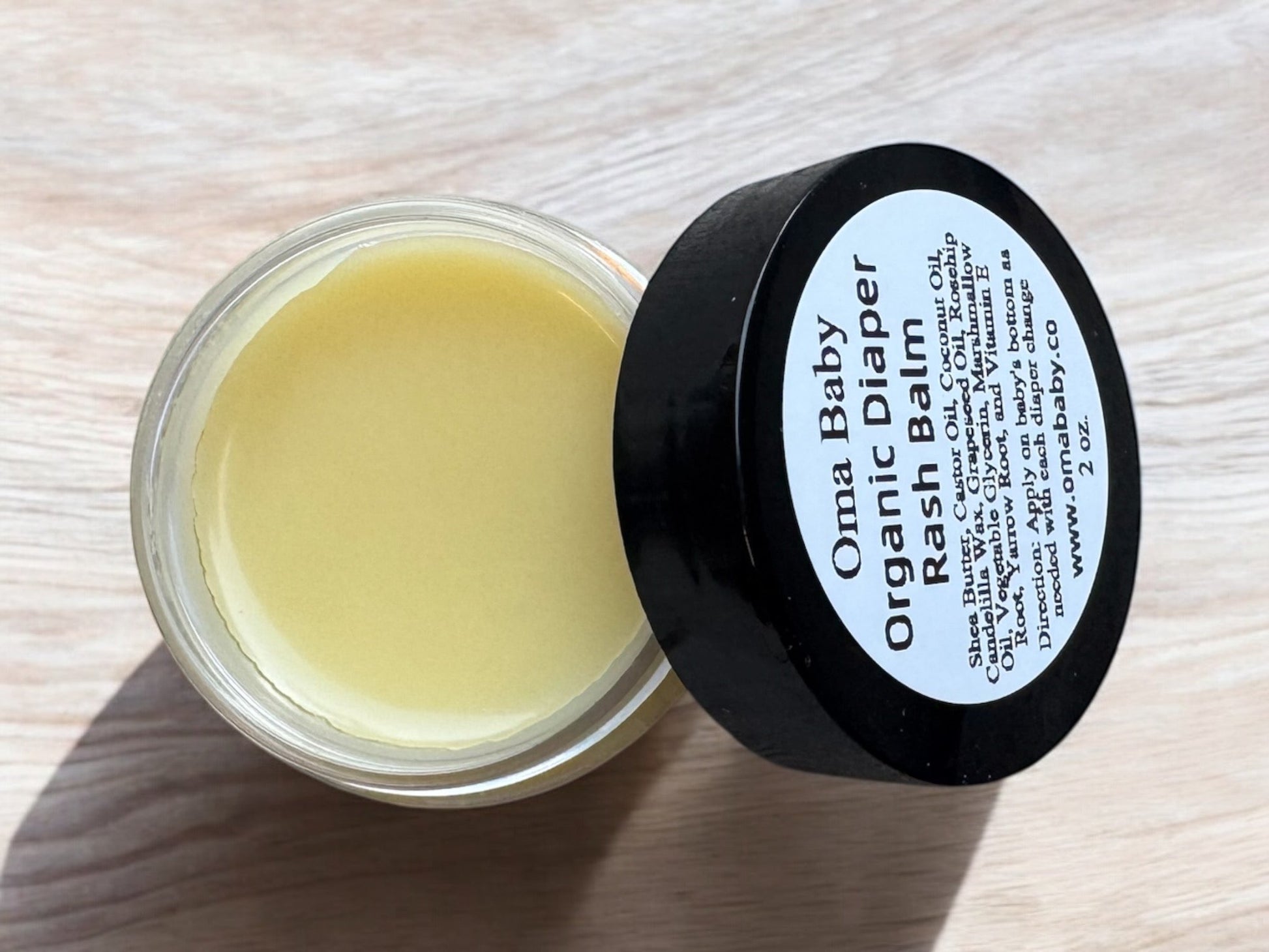 Oma Baby Organic Diaper Rash Balm jar on a light wooden surface