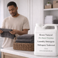 Man folding laundry next to a container of Roses Natural laundry detergent in a laundry room.