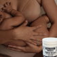Person holding a baby with a container of Ora Baby Herbal Nipple Balm in the foreground.
