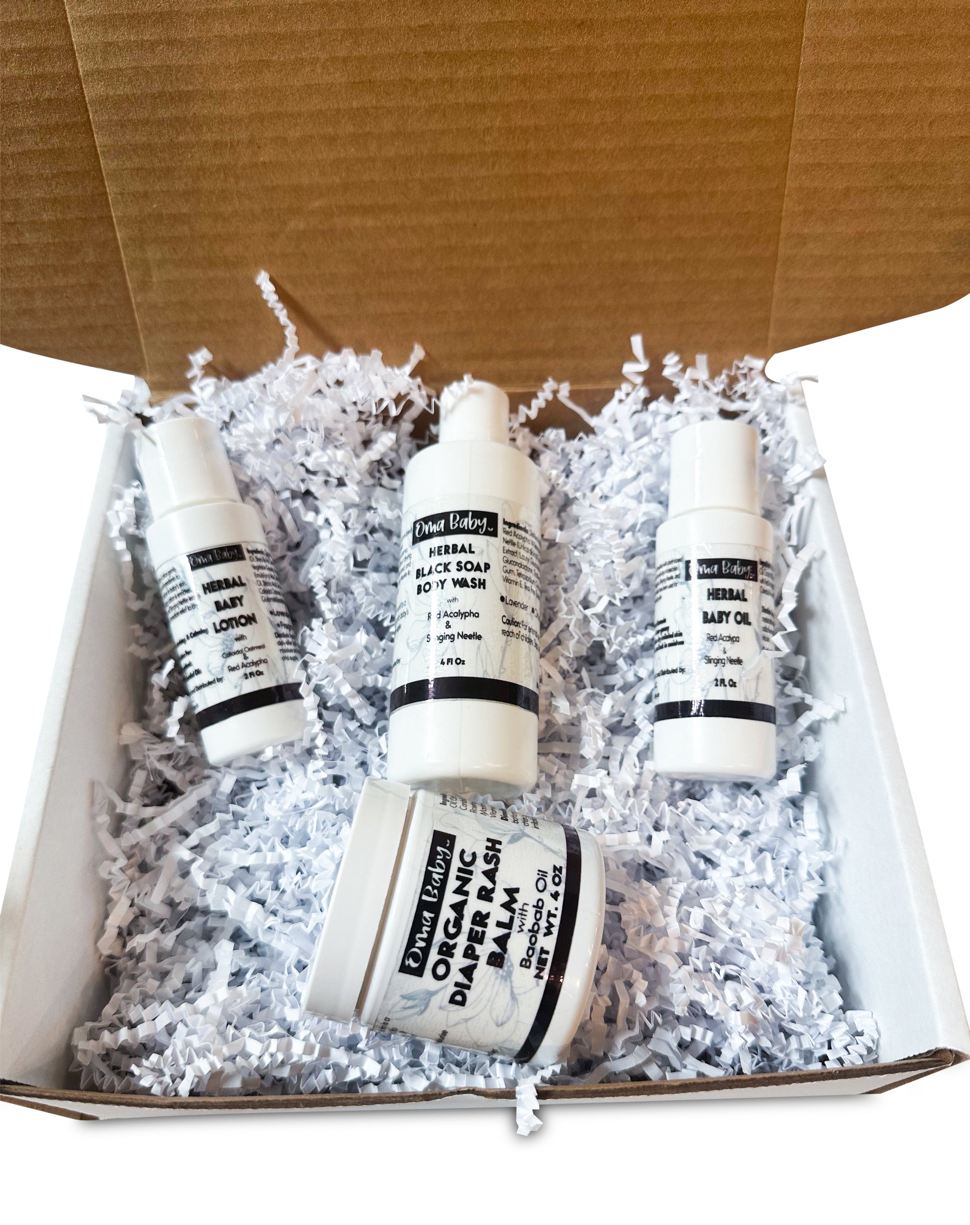 Four bottles of organic baby products in a box with white crinkle paper